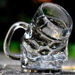 Ein klarer Glasbierkrug, leicht geschmolzen, nach vorne geneigt, auf dem Boden stehend.