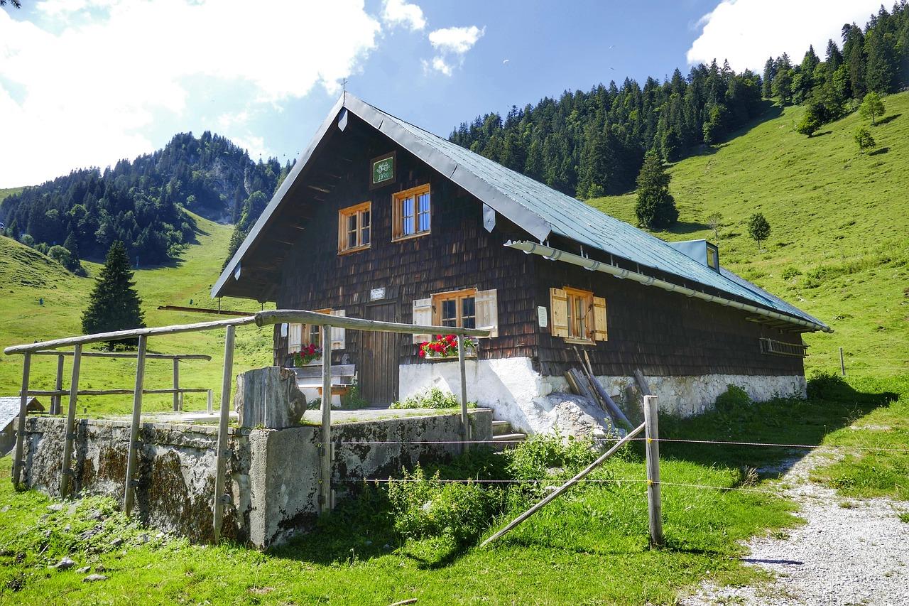 Traditionelle Almhütte mit Holzverkleidung und Fensterblumen in den Bergen.